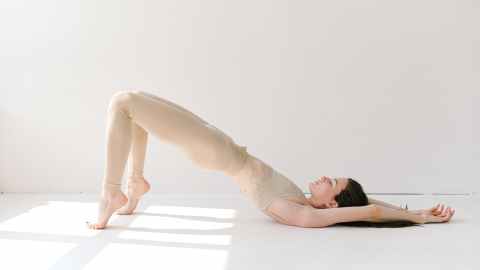 graceful woman performing variation of setu bandha sarvangasana yoga pose