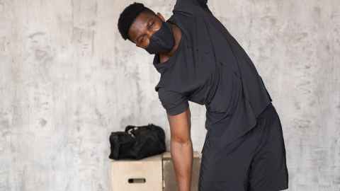 black sportsman in medical mask inclining aside