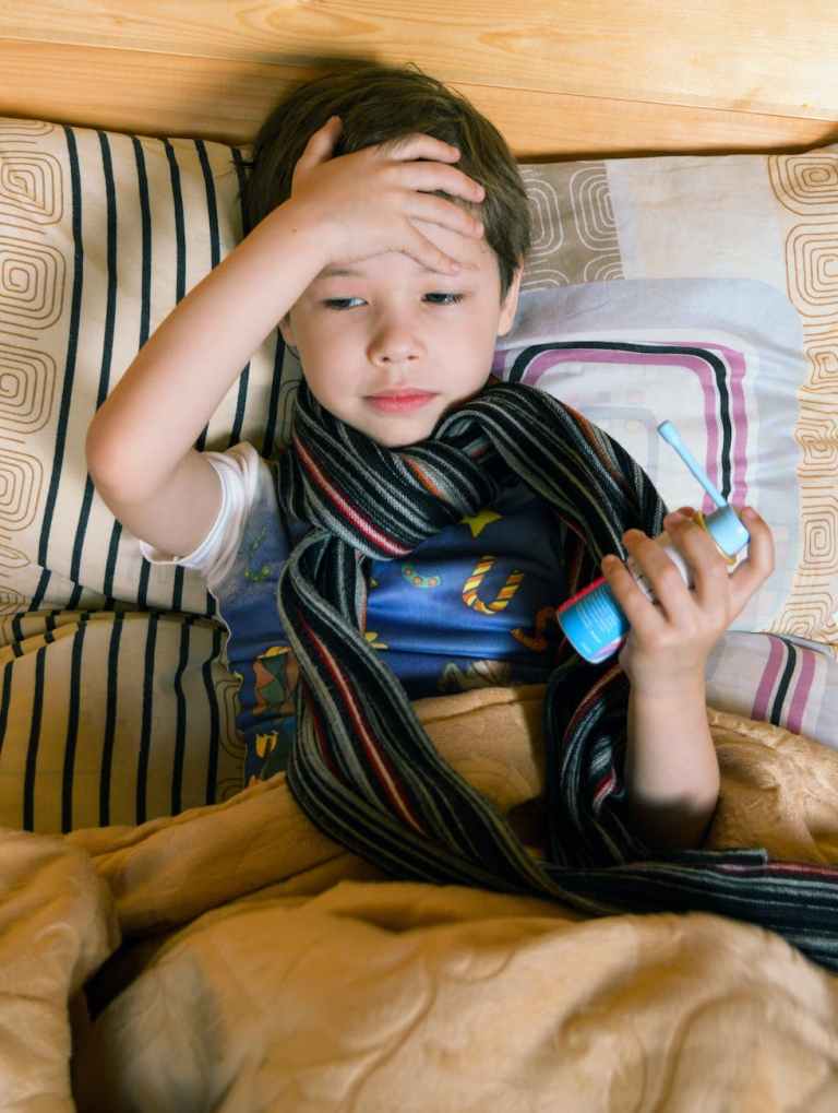 sick boy touching head and holding aerosol drug